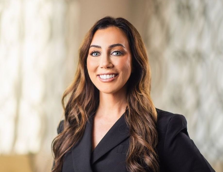 Smiling woman in professional attire, soft background.