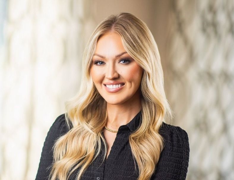 Smiling woman with long blonde hair, black top.