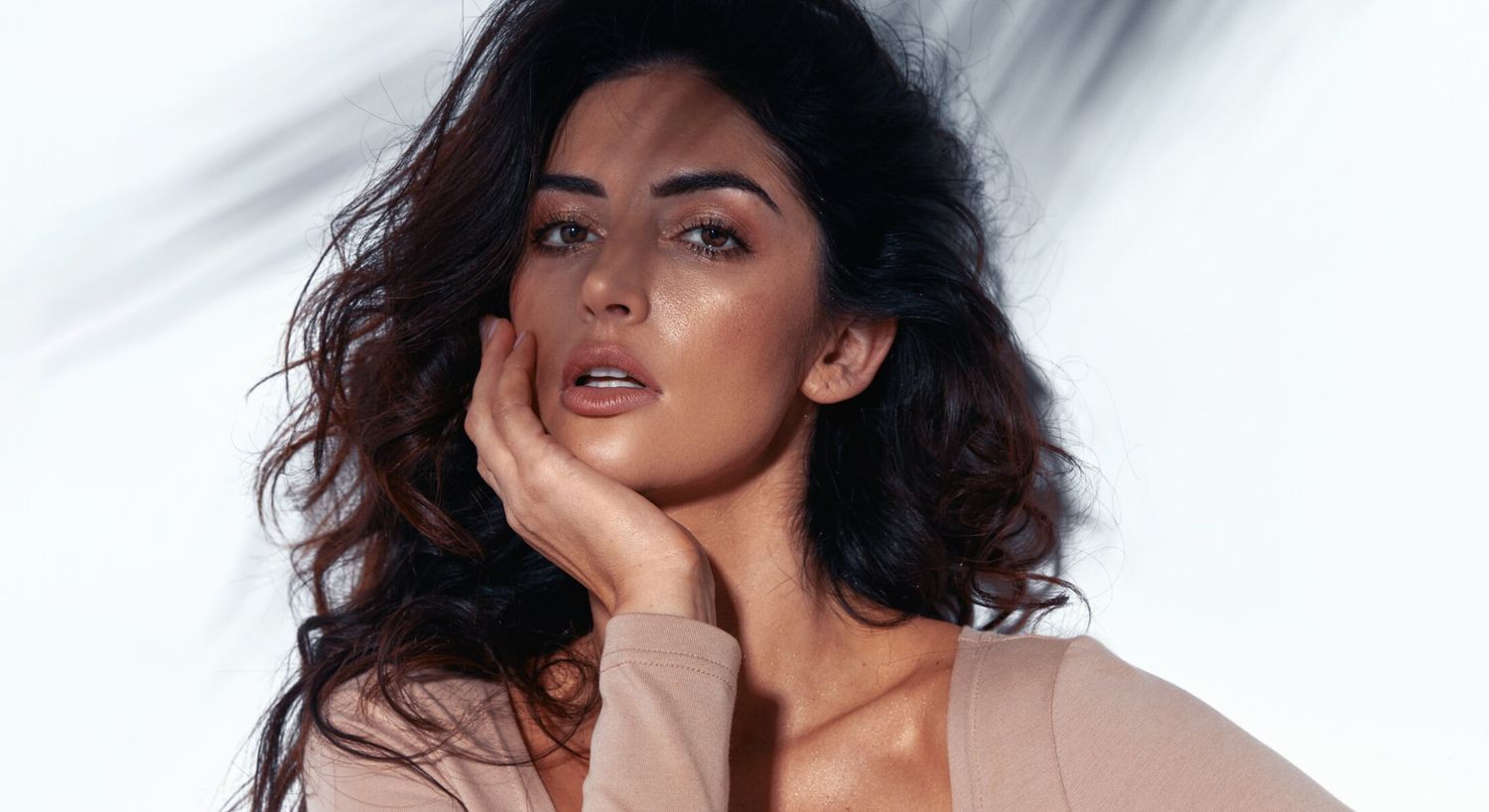 Woman with wavy hair posing thoughtfully.